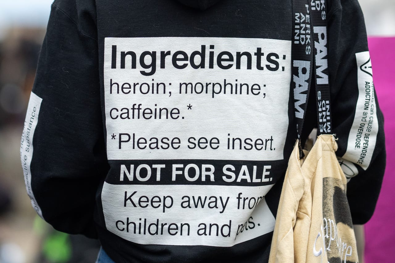 A black hoodie's back reads: 'Ingredients: heroin; morphine; caffeine. NOT FOR SALE.'